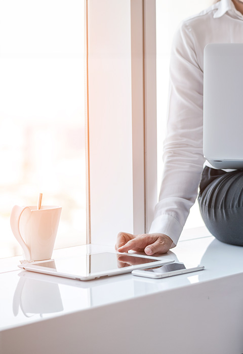 Een hand is bezig met het melden van een schadegeval in MyDVV, terwijl de telefoon binnen handbereik ligt om indien nodig meteen de DVV-consulent te bellen.