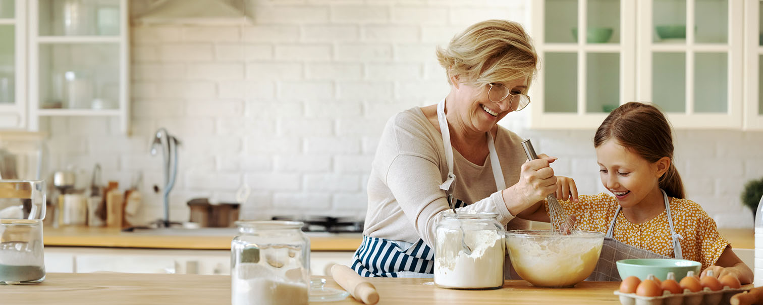 Grand-mère fait et sa petite-fille dans la cuisine pour illustrer la page de l'épargne-pension en branche 23 de DVV