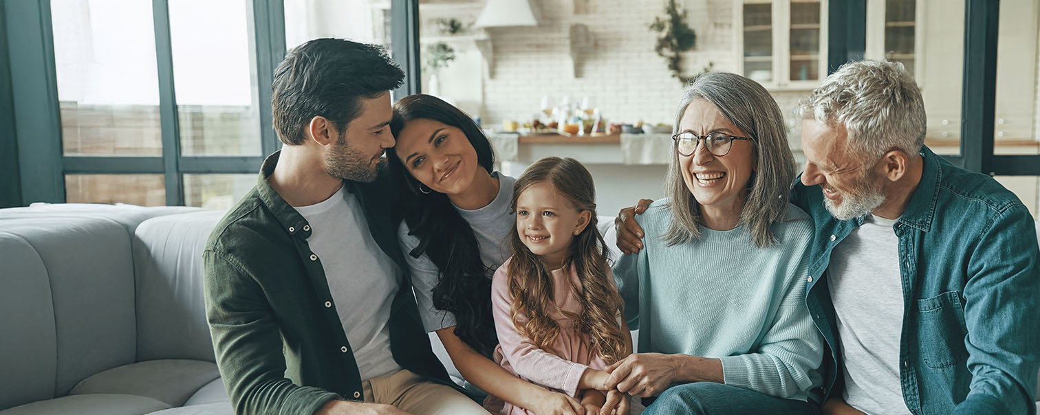 Grands-parents, parents et enfant dans le canapé pour illustrer la page des épargne-pensions de DVV