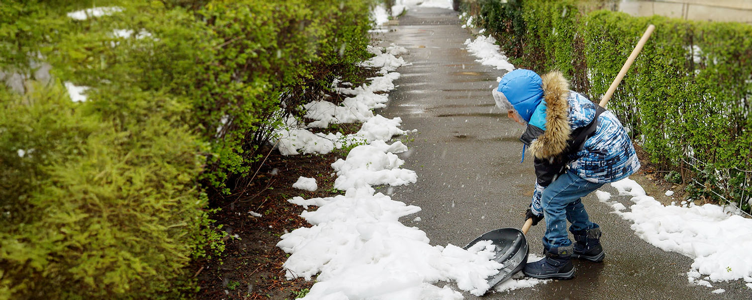 Petit garçon dégageant la neige du trottoir pour illustrer la page comparative des protections juridique dans le cadre privé