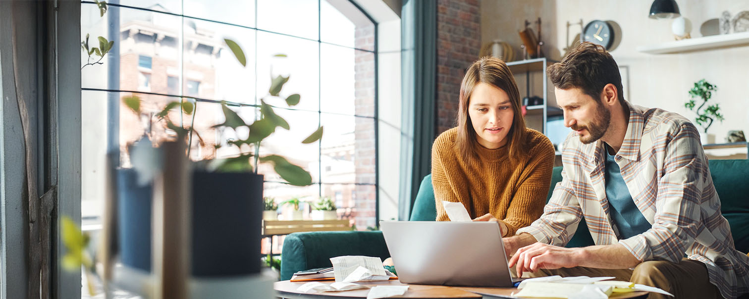 Een koppel raadpleegt documenten op laptop als illustratie van de optie onrechtstreekse verliezen van  de woningverzekering