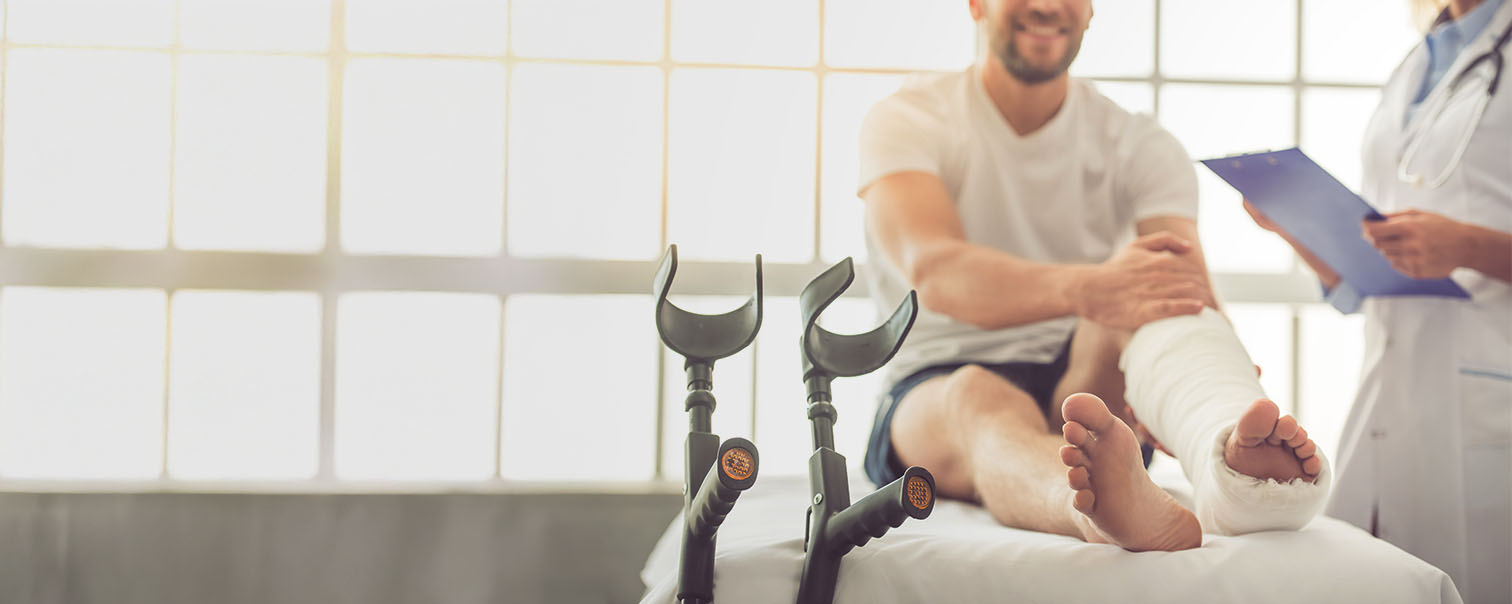 Homme avec jambe dans le plâtre sur la table d'osculation pour illustrer la page des assurances pour maladie et accidents