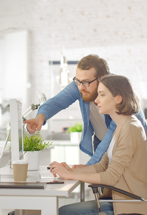 Twee personen bezig op een computer als illustratie van de pagina van de verzekering Alle Risico’s Materieel van DVV