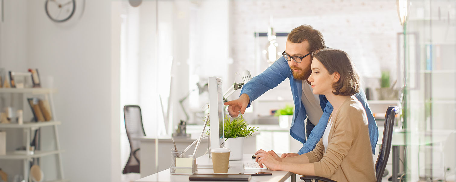 Twee personen bezig op een computer als illustratie van de pagina van de verzekering @rtronic voor hardwarze en software  