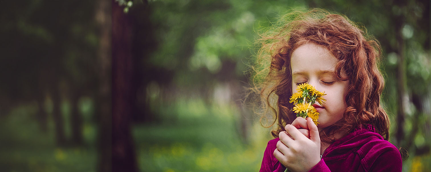 Kindje dat aan bloemen ruikt als illustratie van de pagina overlijdensdekking van verschillende pensioenverzekeringen van DVV 